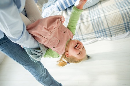 The father plays with the little daughter. The child laughs from pleasure.の写真素材