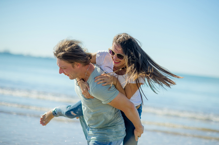 Young man holds on hands beautiful young woman. Couple spends time on the seashore. Summer, sea, good mood.の写真素材