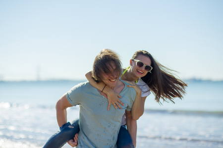Young man holds on hands beautiful young woman. Couple spends time on the seashore. Summer, sea, good mood.の写真素材