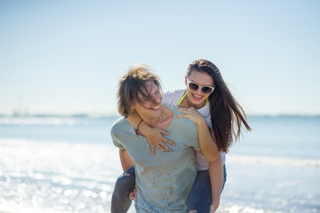 Young man holds on hands beautiful young woman. Couple spends time on the seashore. Summer, sea, good mood.の写真素材