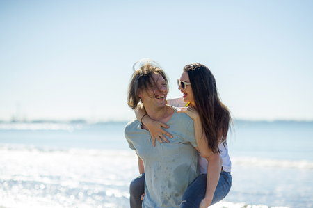Young man holds on hands beautiful young woman. Couple spends time on the seashore. Summer, sea, good mood.の写真素材