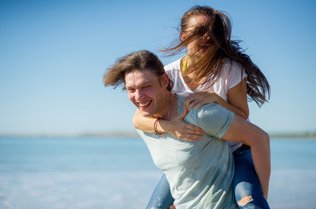 Young man holds on hands beautiful young woman. Couple spends time on the seashore. Summer, sea, good mood.の写真素材