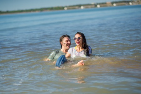 Young couple bathing in the sea. Guy and girl are merrily floundering in the water.の写真素材