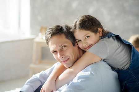 Daughter hugs a father. The girl of school age hugs a dad affectionately.の写真素材