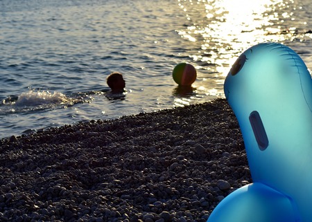 Blue inflatable seal staring at the child playing in the sundownの写真素材