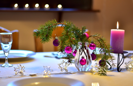Celebration. A colorful laid table decorated different in purple with xmas decoration for a christmas dinner in the dining-room indoors at homeの写真素材