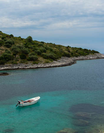 Croatia, Dugi otok,  July 15, 2019: beautiful vertical photo, lonely, white, wooden boat on the sea. Summer concept with clear sea.のeditorial素材