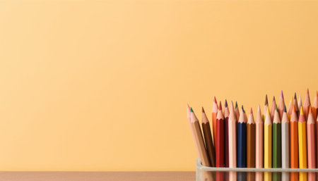 Colorful pencils in a glass vase on a yellow backgroundの素材