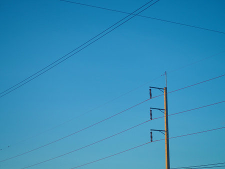 The high voltage light pole fastened to multiple wires leading to On the background is a blue...
