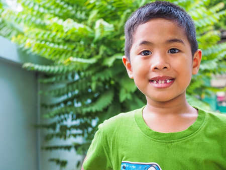 Portrait of a boy Wearing a green shirt With a green tree background.の写真素材