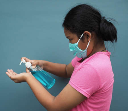 A girl wearing a protective mask And press the alcohol gel to wash your hands.の写真素材