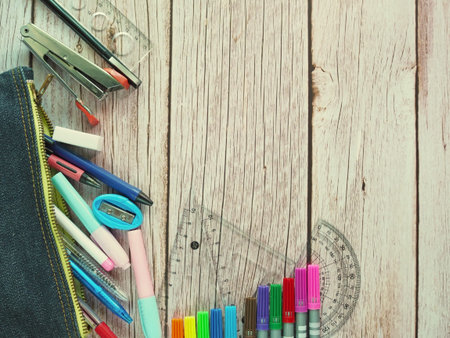 The top view of  stationery in school bags and pencils arranged on a wood teble background.の写真素材