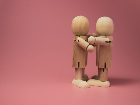 2 wooden dolls hugging each other on a pink background.Concept of social contact from wooden dolls.
