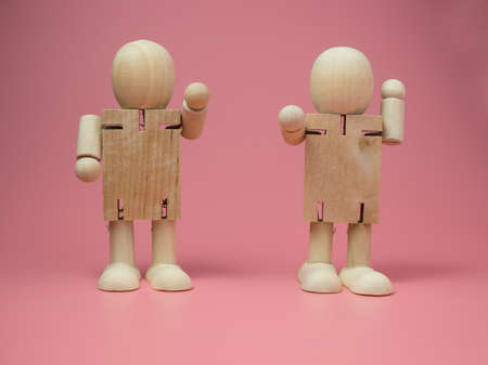 2 wooden dolls standing talk gestures On the pink background.
Concept of social contact from wood dolls.の写真素材