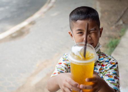 Boy holding a glass of water with a strawの写真素材