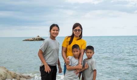 Portraits of mothers and children standing on the rock with the background of the sea.の写真素材