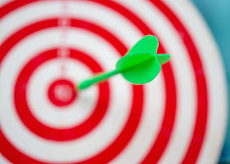 Green arrow strikes center of goal on blurred background - Successful business goal idea.の写真素材