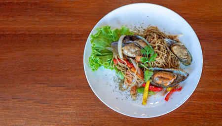 Top view of Spaghetti with Spicy Mix seafood in white plate on the wooden background with copy...