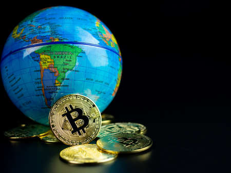 Bitcoin Coins Placed Ahead of a Model World on a black backgroundの写真素材