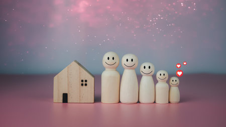 Happy house concept. Model house with wooden dolls standing lined up on pink background and heart icons. Indicates happiness and love in the home.の写真素材