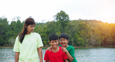 Happy family spending time outdoors hugging and enjoying the view of river. Mother with two kids.の写真素材