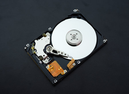 Disassembled open hard disk drive HDD of computer or laptop lies on dark matte surface. Ð¡omputer hardware and equipment. Harddisk data storage.の写真素材
