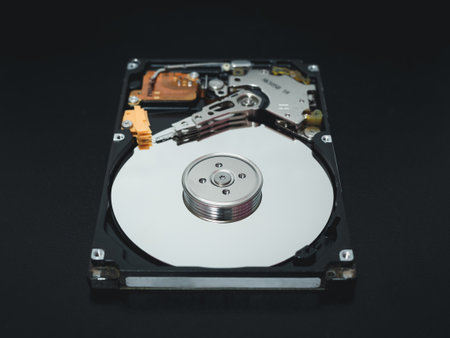 Disassembled open hard disk drive HDD of computer or laptop lies on dark matte surface. Ð¡omputer hardware and equipment. Harddisk data storage.の写真素材