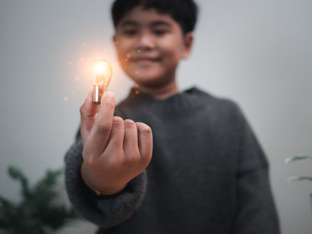 The boy is holding a light bulb. It represents the concept of education, learning, innovation, and success.の写真素材