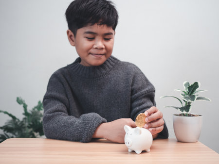 A boy putting coins into piggy bank. Learning financial responsibility and projecting savings. savings concept. investment concept.の写真素材