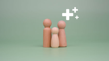 The concept of health insurance and medical welfare. Family of model wooden doll and plus sign on a...