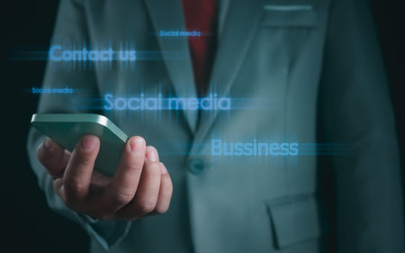 Close-up shot of businessman holding smartphone on dark background Represents business communication...
