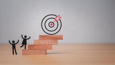 Company employees climb the square wooden steps to reach the dart board. It represents the concept of business strategy and target action plan.の写真素材