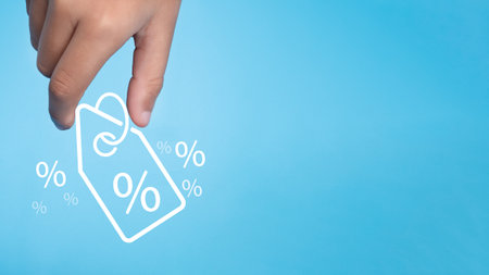 Human hand holds discount percentage sign icon on light blue background represents online shopping concept, special price products and promotions.の写真素材