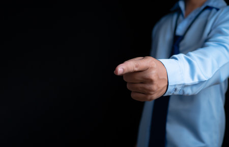 Employee makes a forward pointing gesture on a dark background.の写真素材