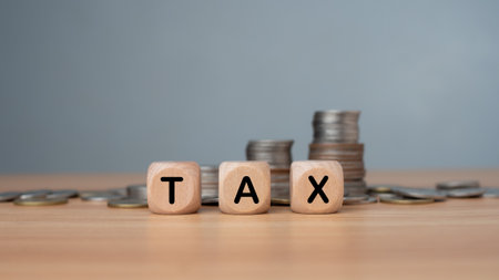 Tax wording print screen on wooden cube block and  coins stacking for tax growth and planning concept, paying tax rates, collecting taxes.の写真素材