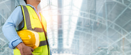 Civil engineer architect standing holding a safety helmet on construction site background,...
