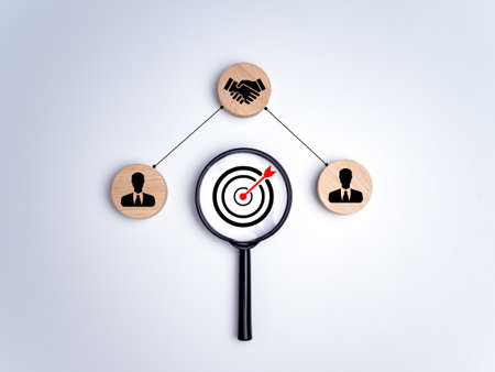 Magnifying glass with dart board and circular pieces of wood printed with human symbols, cooperation, teamwork, training, Collaboration and cooperation, Social connections, joining to solve tasks.の写真素材