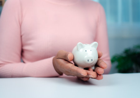 Close-Up Woman Hand holding a piggy bank for saving money and financial concept, Business Banking and Financial Concept. Saving money for retirement funds and insurance concept.の写真素材