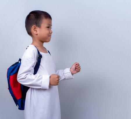 Asian cute boy wearing white and carry student backpack, Boy standing on white background, Lifestyle of a boy on a white background, He looks happy and content.の写真素材