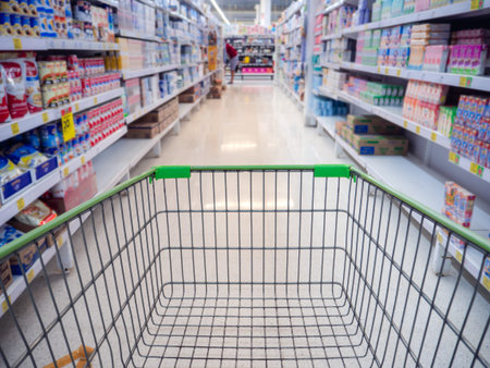 Trolley in department store Abstract blurred of colorful shelves, Shopping cart in supermarket. Empty red shopping cart view with warm light.