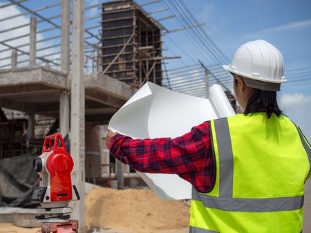 Woman engineer working at site of a large building project, Foreman holding blueprint project working outdoors building side with blueprints on a worksite, Engineering and architecture concept.の写真素材