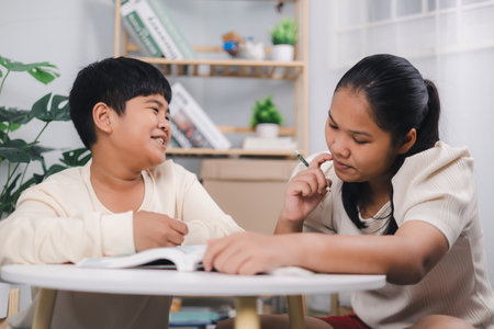 Teacher or sister helping boy writing lesson and learning to write; Female tutor helping little elementary school boy with homework during individual lesson at home; Education home school concept.の写真素材