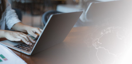 Person typing on laptop keyboard while analyzing documents