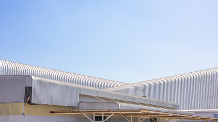 Factory industry, Modern geometric warehouse, Corrugated metal texture background, Architectural building wall with aluminum siding on blue sky background, Stackable warehouse roof, Metal sheet roof.の写真素材