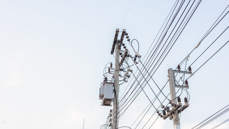 Electrical energy transfer distribution on concrete pole against white sky background, AC...