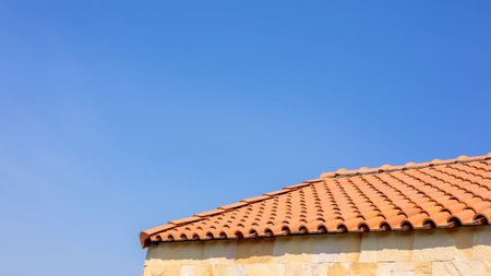 The roof tiles of the building have a background of blue skies. Clay tile roof close up on blue sky...