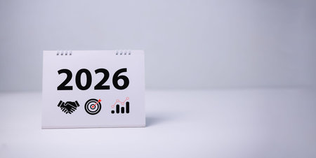 Desk calendar displaying 2026 with business-themed icons like handshake, target, and growth chart...