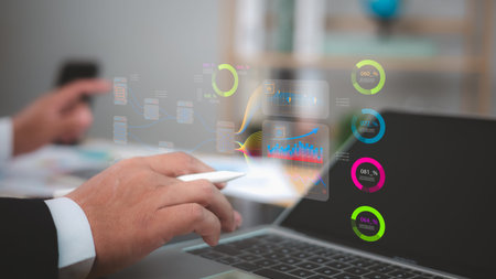 Business professional analyzing holographic data visualizations, charts, and metrics above a laptop....