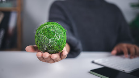 Environmental protection is symbolized by a moss covered green globe with a translucent world map held in hand, representing sustainability, ecological care, and global conservation efforts.の写真素材