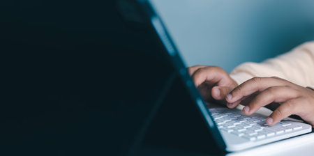 Close-up of hands typing on modern laptop keyboard, representing productivity, remote work, study,...
